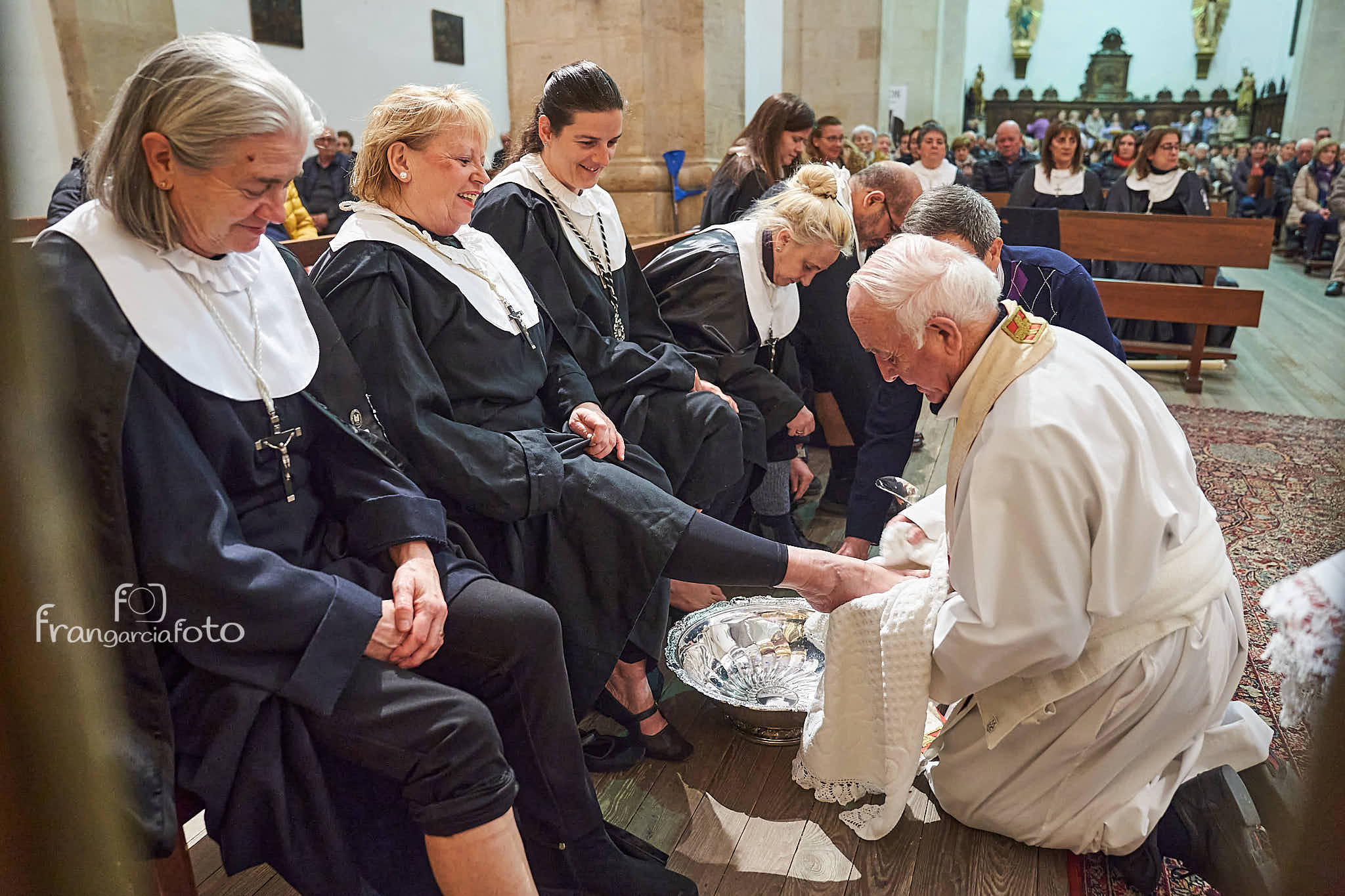Sacerdote lavando los pies de una hermana cofrade
