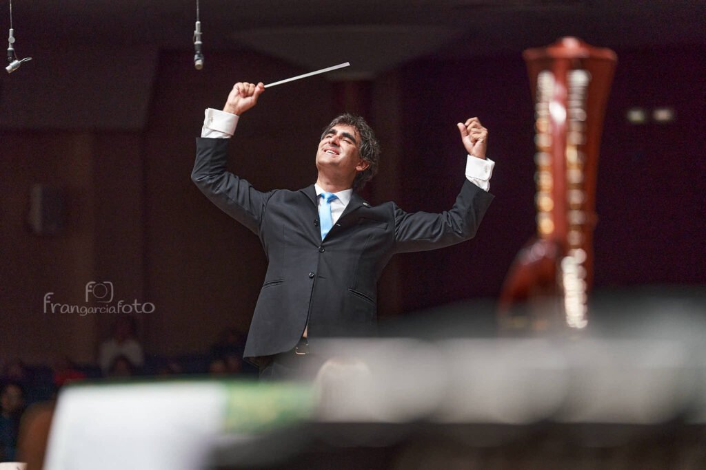 Director de Orquesta dirigiendo sus músicos en un auditorio