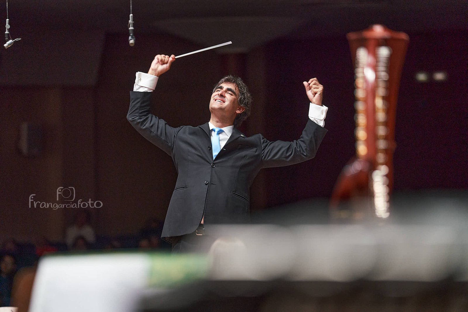 Director de Orquesta dirigiendo sus músicos en un auditorio